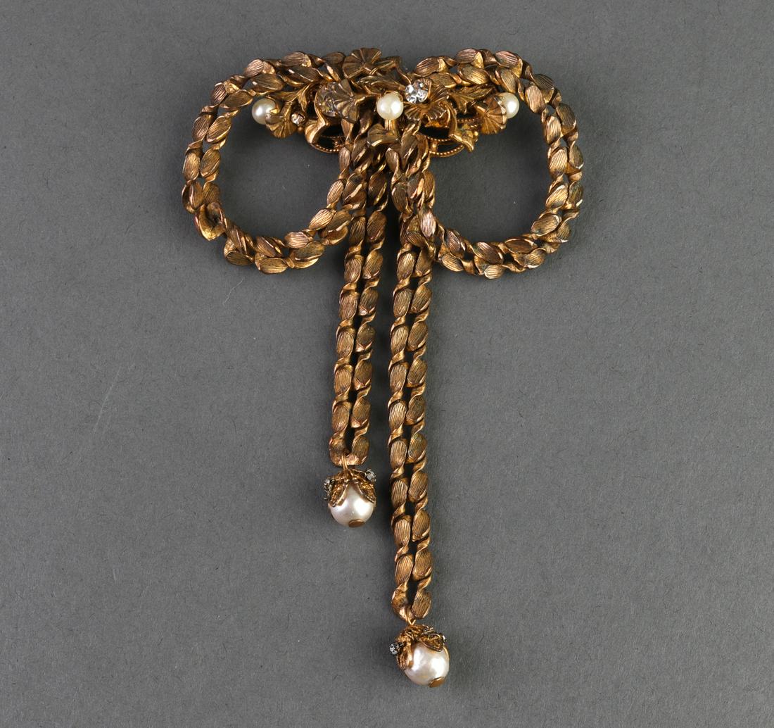 Miriam Haskell Faux Pearl and Crystal Bow Brooch: Miriam Haskell faux pearl and crystal brooch stylized as a bow with foliate detailing throughout, hallmarked to reverse. 4.75" L x 3.25" W. Missing crystal.