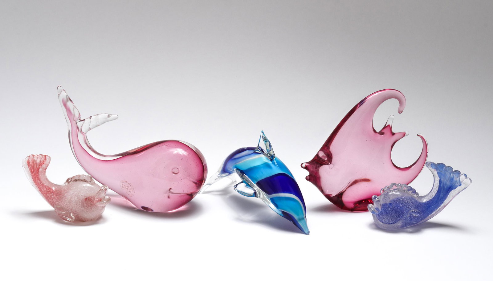 Murano Glass Marine Life Figures, Group of 5: Murano art glass marine life figures, group of five including a Franco Moretti whale, three fish, and a blue and white dolphin. Whale: 4.5" H x 6.5" L.
