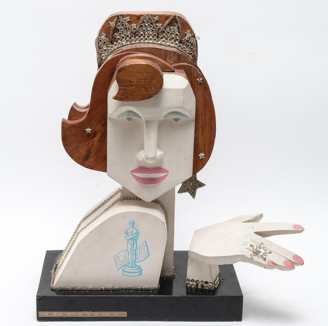 Donn Russell "Fame Means Nothing" Sculpture: Donn Russell (American, b. 1929) "Fame Means Nothing to Me, Darling," polychrome painted wood sculpture, depicting a woman with tiara and jewelry, painted with an Oscar award and inscribed with names
