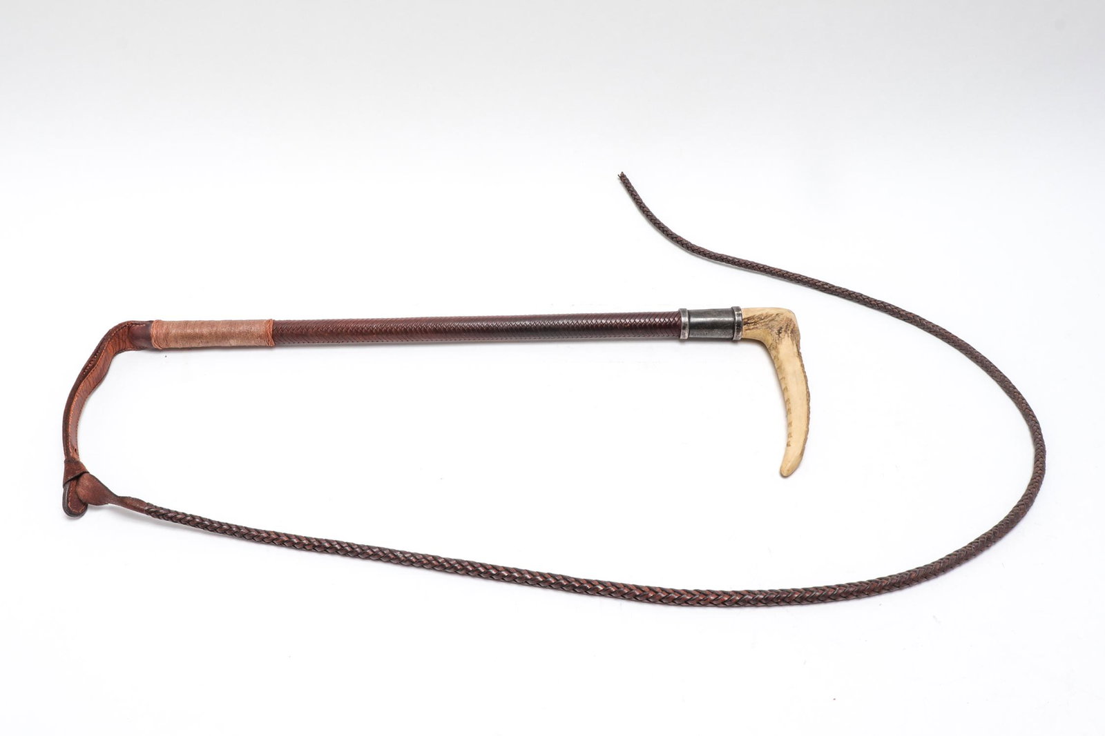 Swaine Adeney Antler, Leather & Silver Riding Whip: Early 20th century English riding whip, woven leather with sterling silver collar bearing hallmarks, and antler handle with makers plaque. Approximately 71" L.