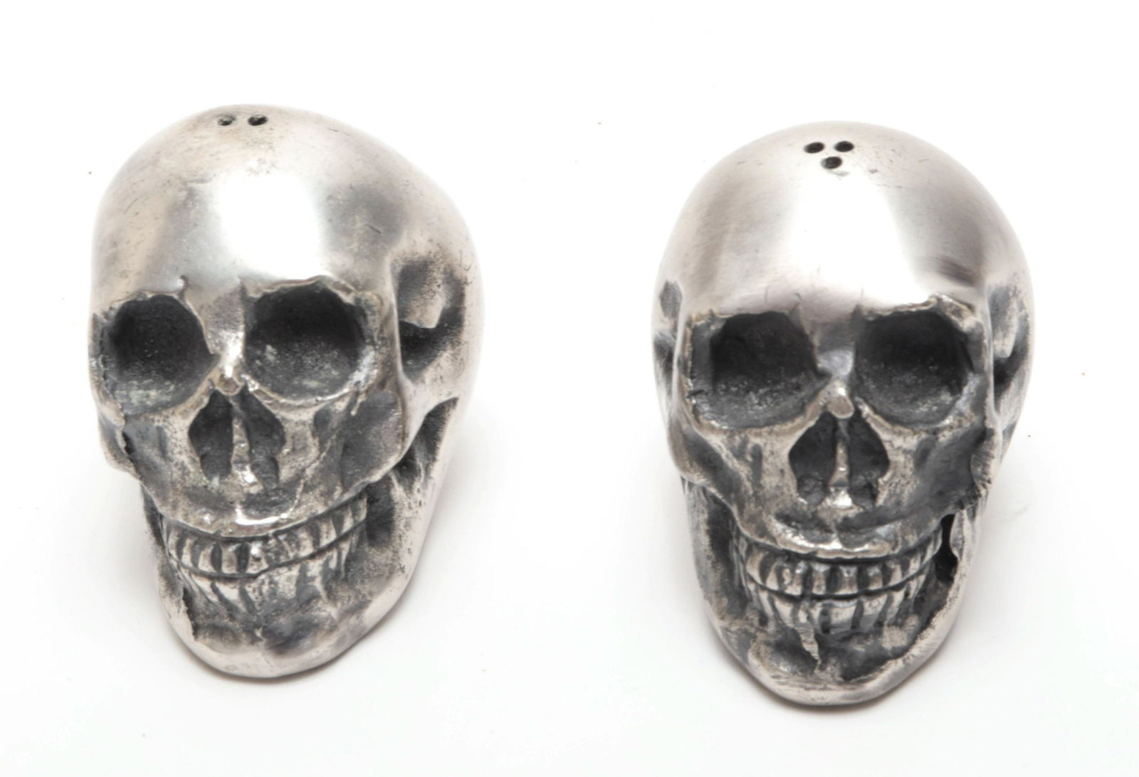 Modern Cast Metal Skull Form Salt & Pepper Shakers: Pair of modern cast metal skull-form shakers. 2" H x 2" W. Property from the Estate of designer, model, television host, and business woman, Nina Griscom.
