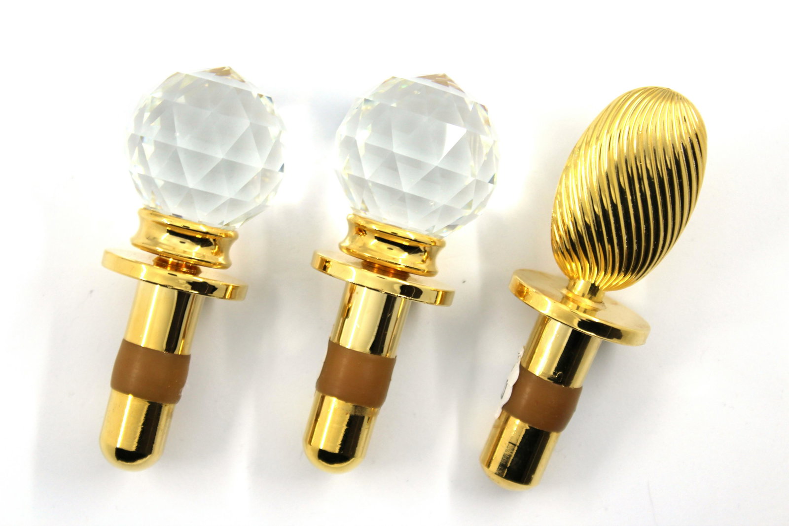 Hans Turnwald Crystal Bottle Stoppers, Group of 3: Hans Turnwald bottle stoppers, group of three, two with faceted crystal tops and one with gold-tone metal oval top, all marked "Hans Turnwald / Made in USA / Design Registered." Largest: 4.25" L.