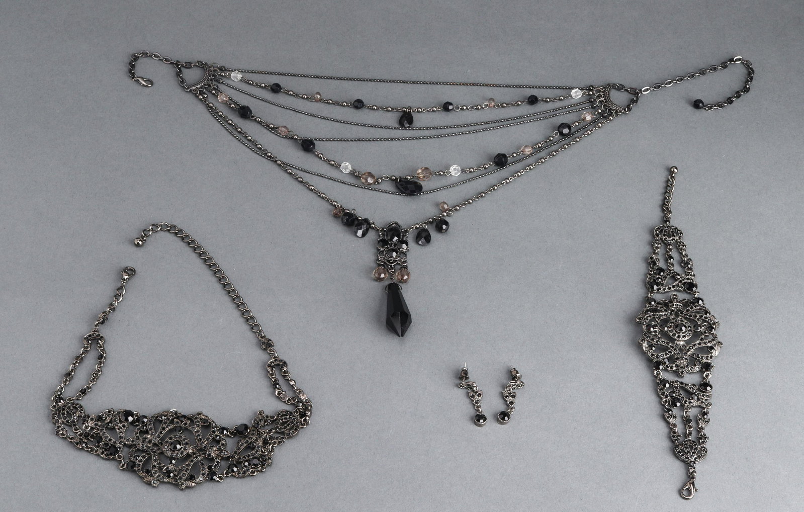 Women's Mourning Jewelry Style Demi-Parure: Women's silver-tone metal and black glass mourning jewelry style demi-parure in the Victorian or Edwardian style, consisting of a necklace, pair of matching bracelets, and pierced earrings. Necklace: 