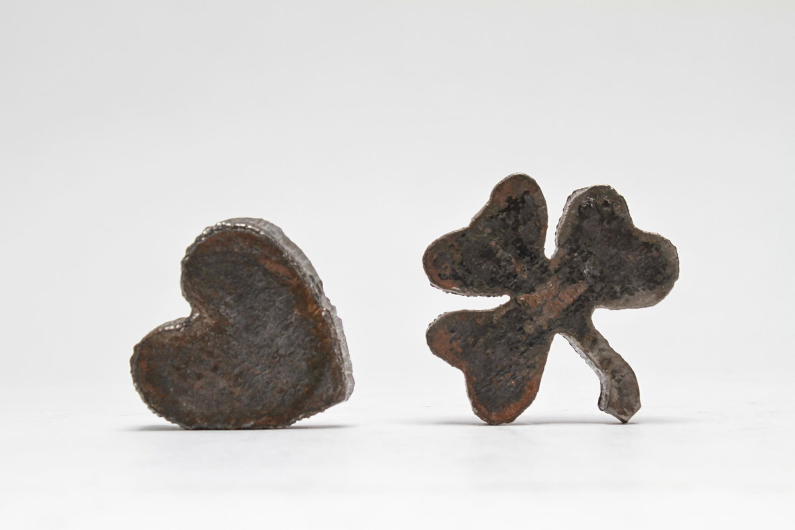 Alan Wilson Cut-Steel Paperweights Clover & Heart: Alan Wilson (American, 20th C.) cut-steel paperweights, two pieces, the first a clover form bearing impressed maker's mark and dated 1969; the second a heart, unmarked. Largest 2.75" L.