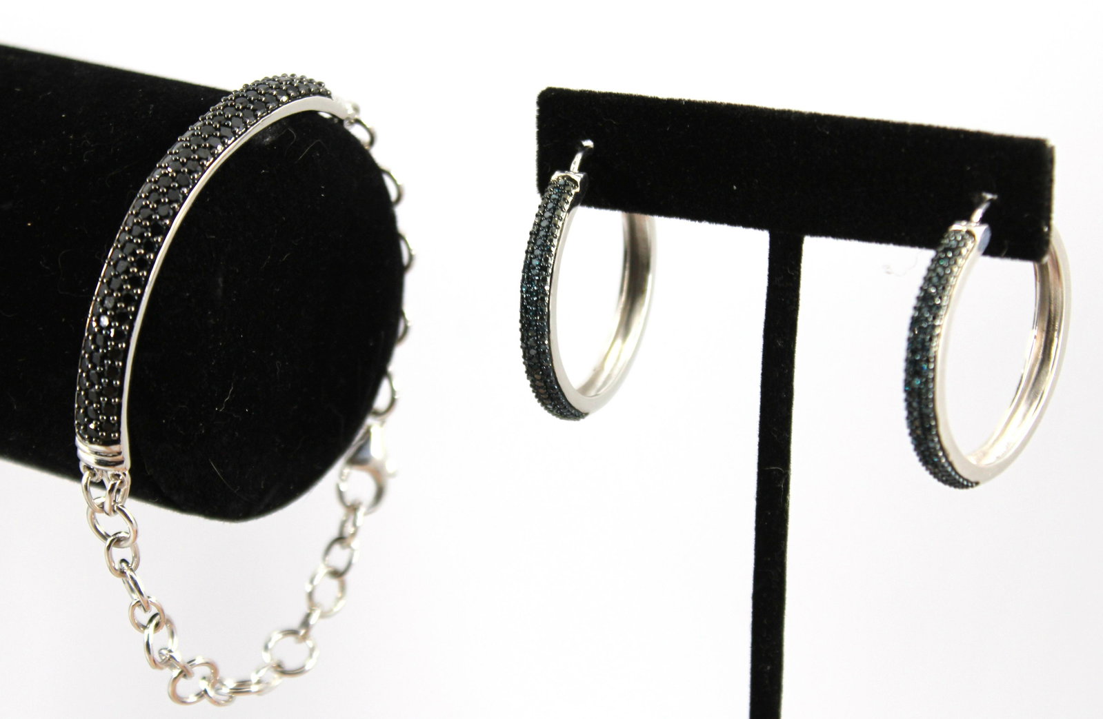 Modern Silver Blue Diamond And Spinel Jewelry: Two items comprising a pair of hoop earrings with a short band of blue diamonds set in a row of three, black spinel band bracelet with chain link terminals and lobster claw clasp. Blue diamond weight 