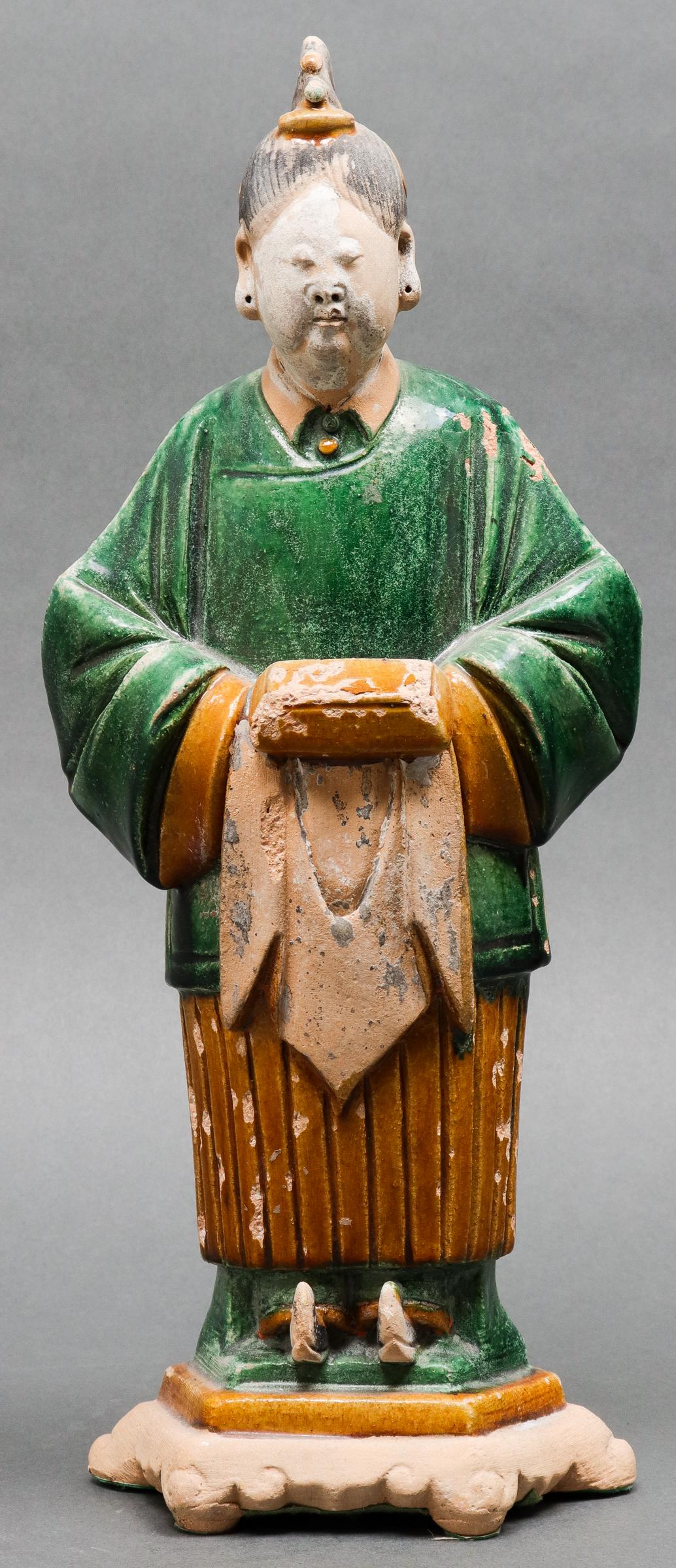 Chinese Ming Dynasty Sancai Pottery Attendant: Chinese Ming Dynasty (1368-1644) green and ochre sancai glazed pottery burial figure of an attendant standing on hexagonal base. 14.25" H x 6" W x 4" D. Crazing and minor losses to glaze.