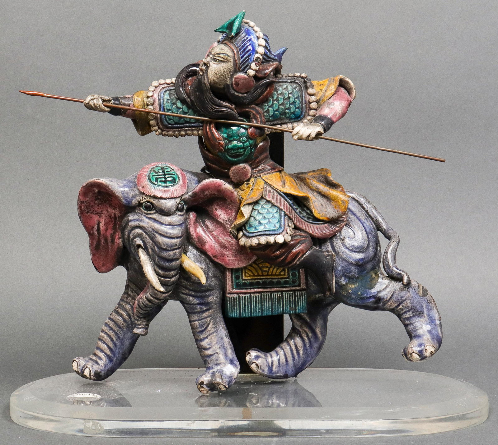 Chinese Ming Dynasty Style Elephant Ride Roof Tile: Chinese Ming Dynasty style ceramic roof tile depicting elephant and warrior with weapon, mounted to lucite and acrylic stand with partial "Christie's" label. Overall: 12" H x 14" W x 6.5" D; tile: 11"