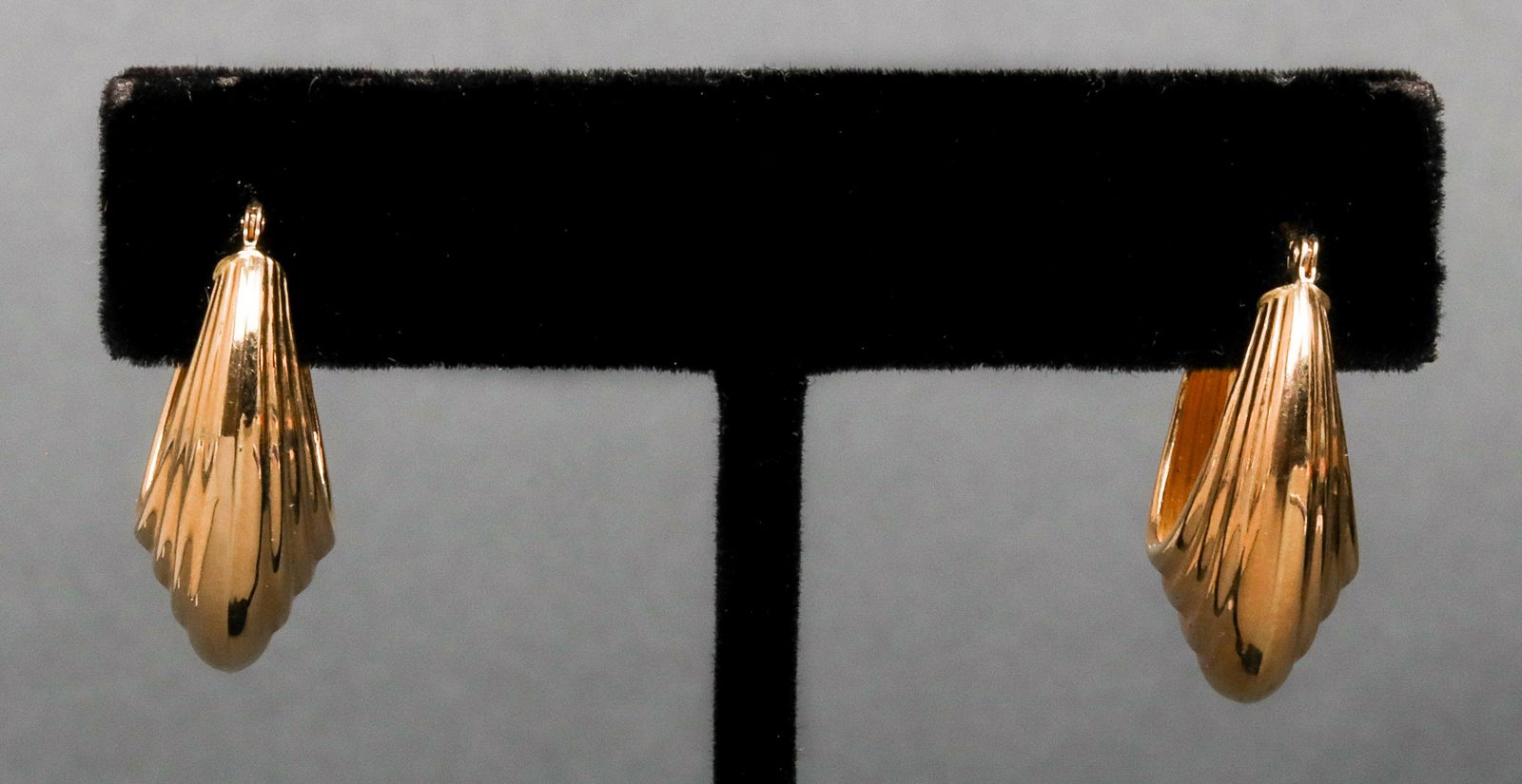 14K Yellow Gold Ribbed Oblong Oval Hoop Earrings: 14K yellow gold ribbed oblong oval hoop earrings, marked: "14K / JCM." 0.937" L x 0.375" W. Approx: 1.2 dwt.