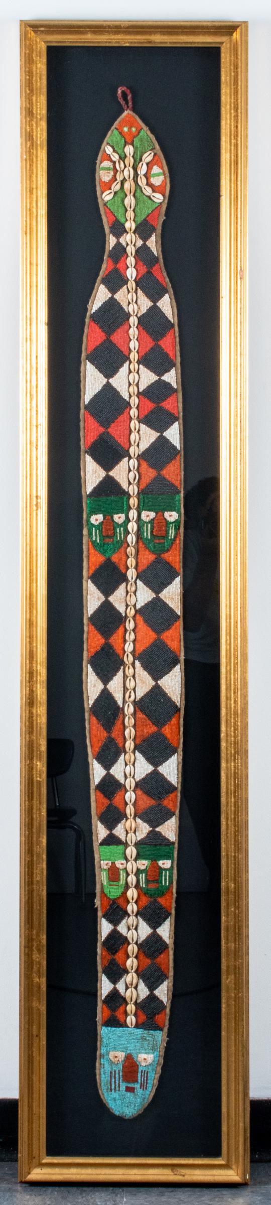 West African Ceremonial Bead & Shell Belt: West African, likely Ghana, ceremonial belt with beaded mask and geometric designs and cowrie shell accents, mounted behind glass in frame. Belt approx: 63" L x 6.25" W; frame: 73.5" H x 14.25" W x 1.