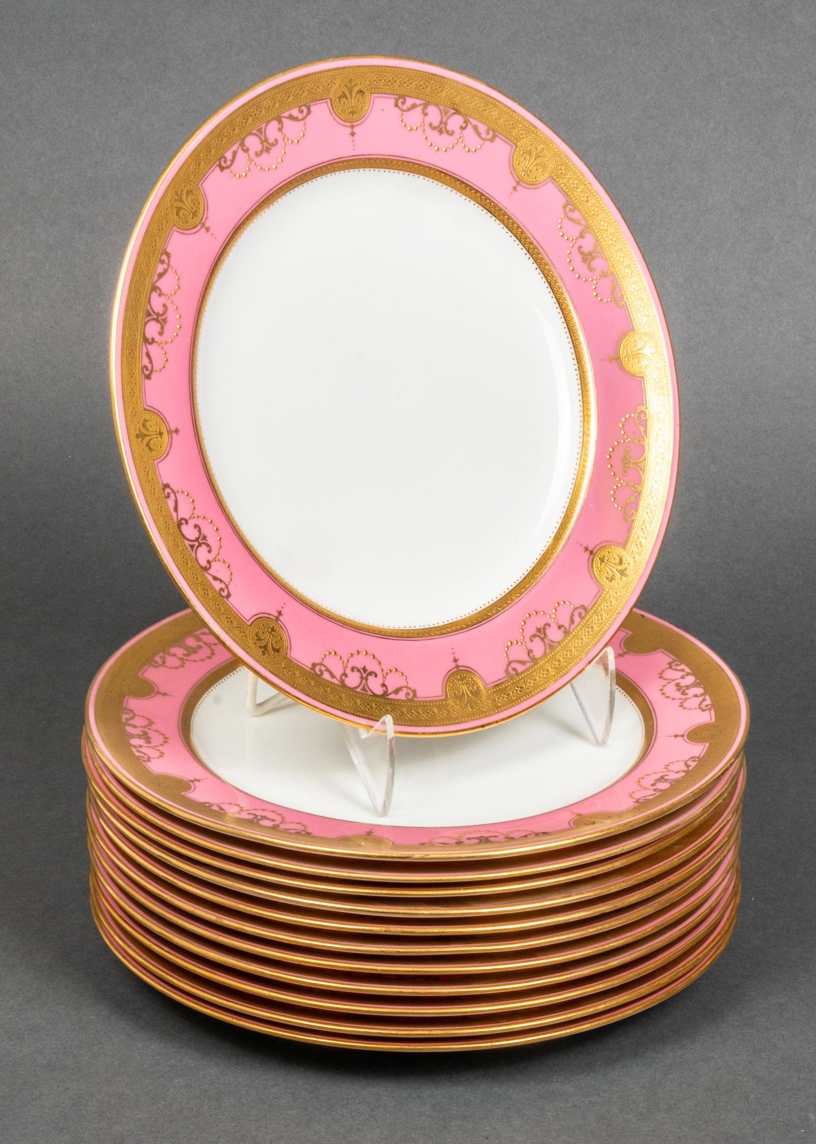 Minton's English Porcelain Gilt-Trimmed Plates, 12: Minton's English porcelain luncheon plates, set of 12, pink rims with gilt trim, maker's mark underside along with retailer's mark for Gauche-Connor Co. New Orleans. 9" diameter.