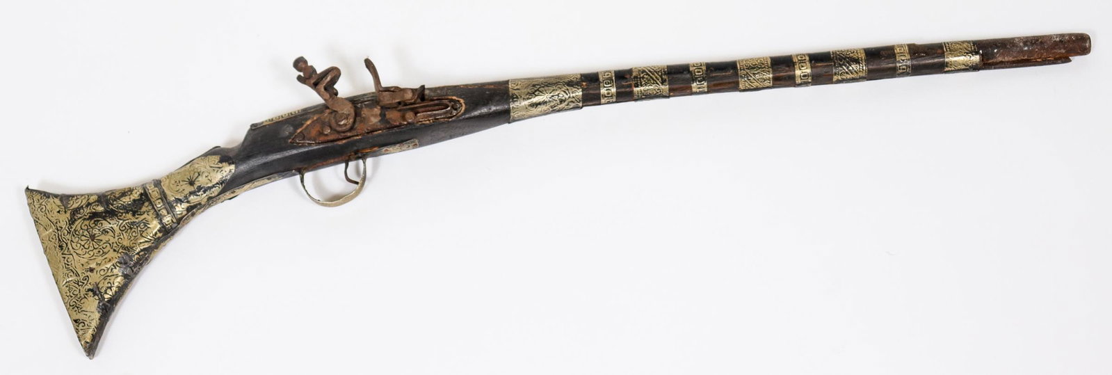 Antique Indian Flintlock Rifle: Antique Indian flint lock rifle, decorative incised metal sheets applied to wood. 6" H x 33" L. x 2." D.