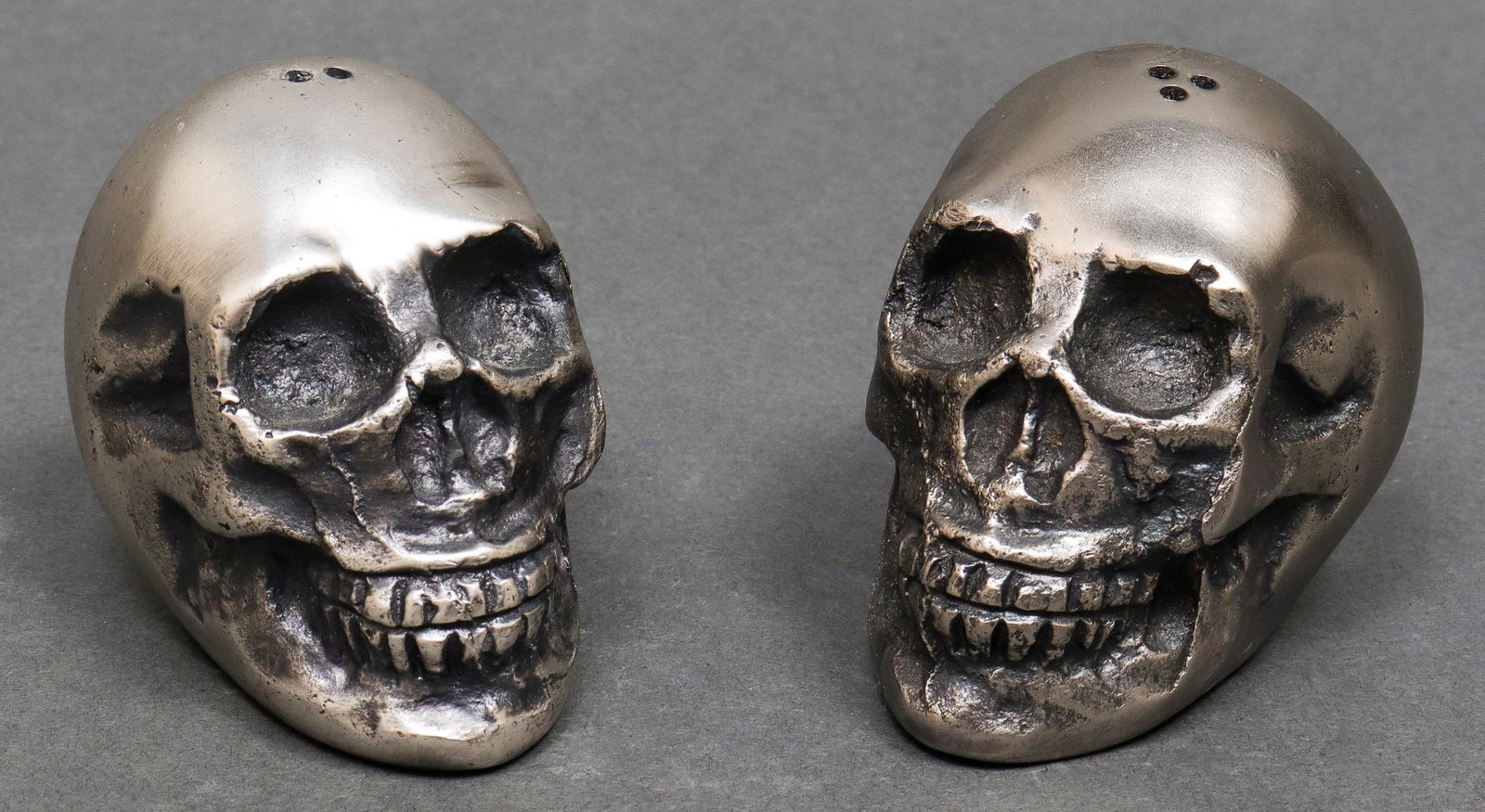 Modern Cast Metal Skull Form Salt & Pepper Shakers: Pair of modern cast metal skull-form shakers. 2" H x 2" W. Property from the Estate of designer, model, television host, and business woman, Nina Griscom.