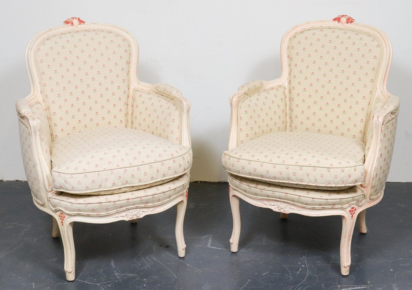 Louis XV Style Petite Bergers, Pair: Pair of Louis XV style bergeres / armchairs, carved and painted frames with rose covered upholstery, with dusty-rose painted surmount to crest rail. 32" H x 23" W x 21" D.
