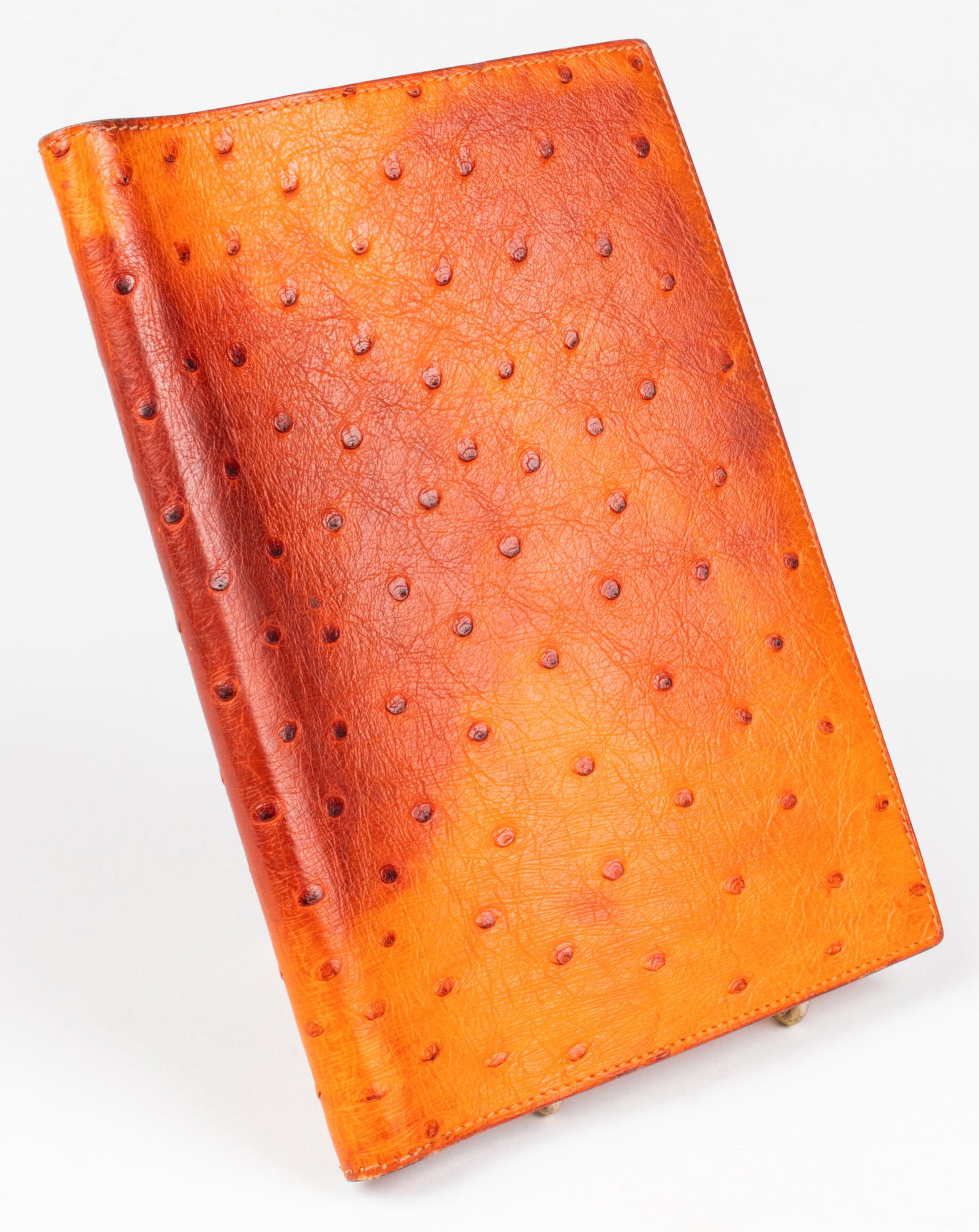 Hermes Orange Ostrich Globe Trotter Agenda Cover: Hermes orange ostrich leather Globe Trotter agenda cover, the exterior opens to reveal two pockets and double hooks for holding a notebook, stamped "Hermès Paris Made In France." 7” H x 5.25” W x