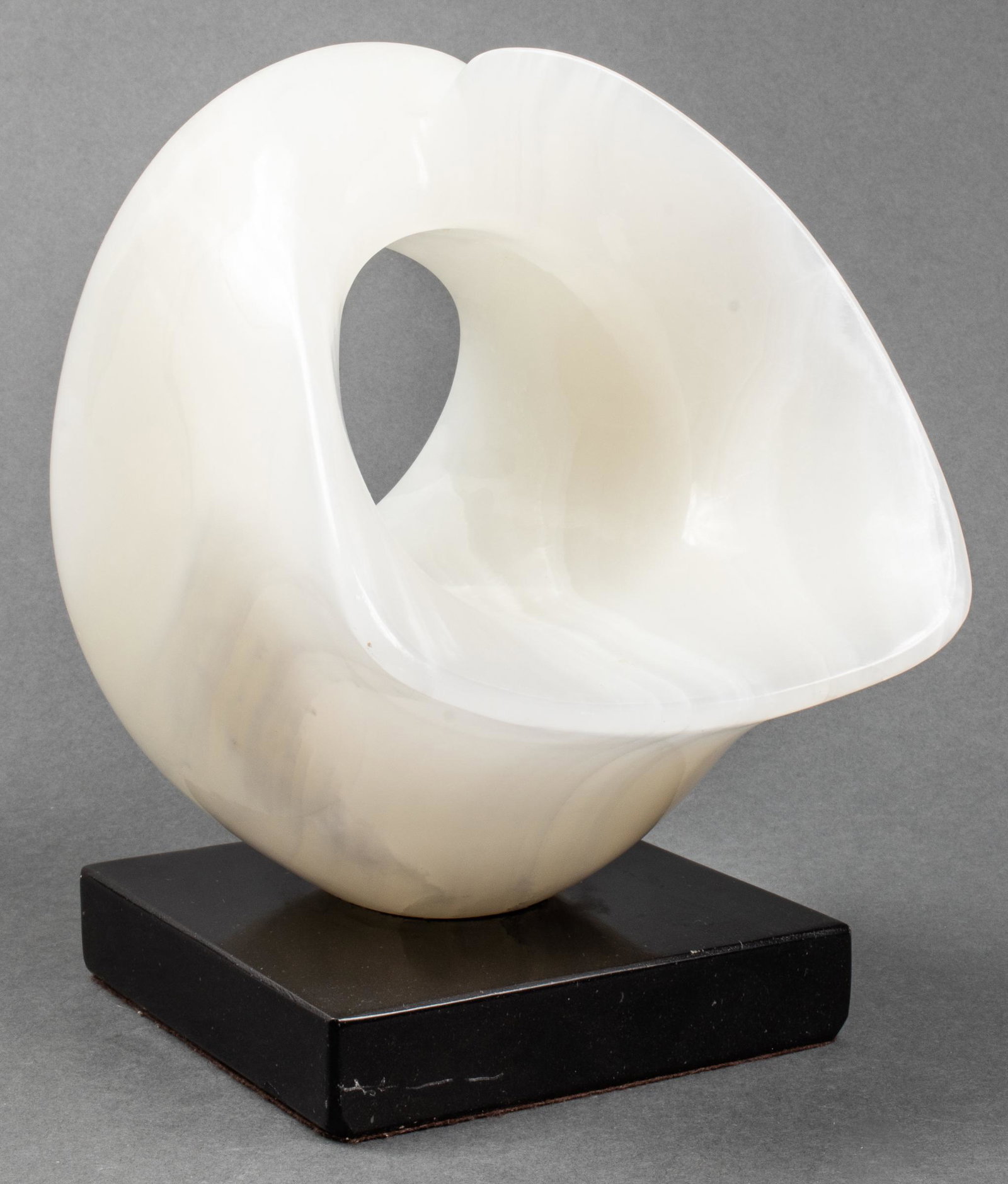 Modern Abstract Biomorphic Carved Onyx Sculpture: Modern abstract white onyx sculpture of biomorphic form, mounted to black stone base. 10" H x 8" W x 7" D.