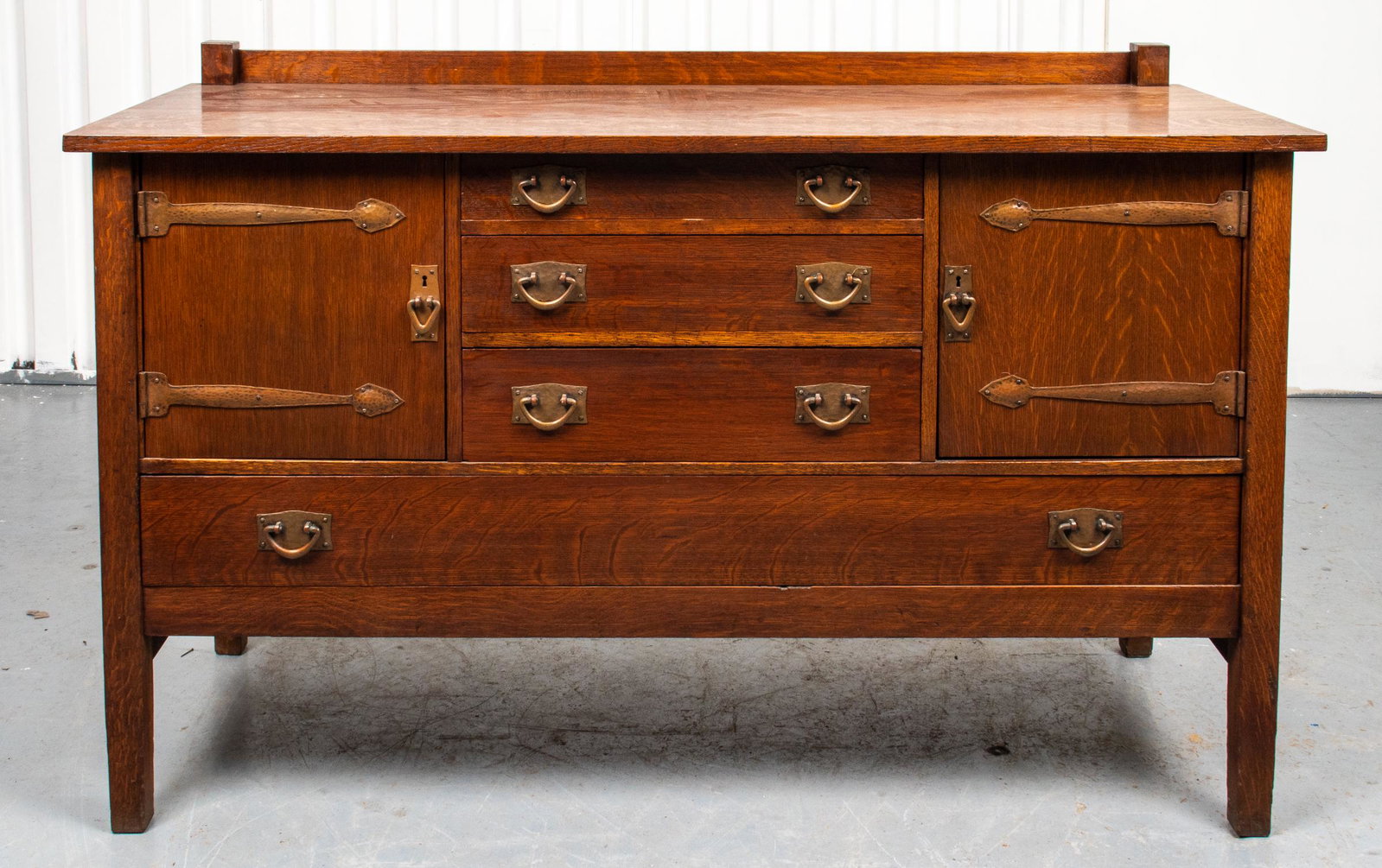 Stickley Mission Oak Sideboard: Stickley oak sideboard with copper hardware, Mission / Arts & Crafts design, two cupboard doors and four drawers, reverse with label remnant. 39.5” H x 62” W x 24” D.