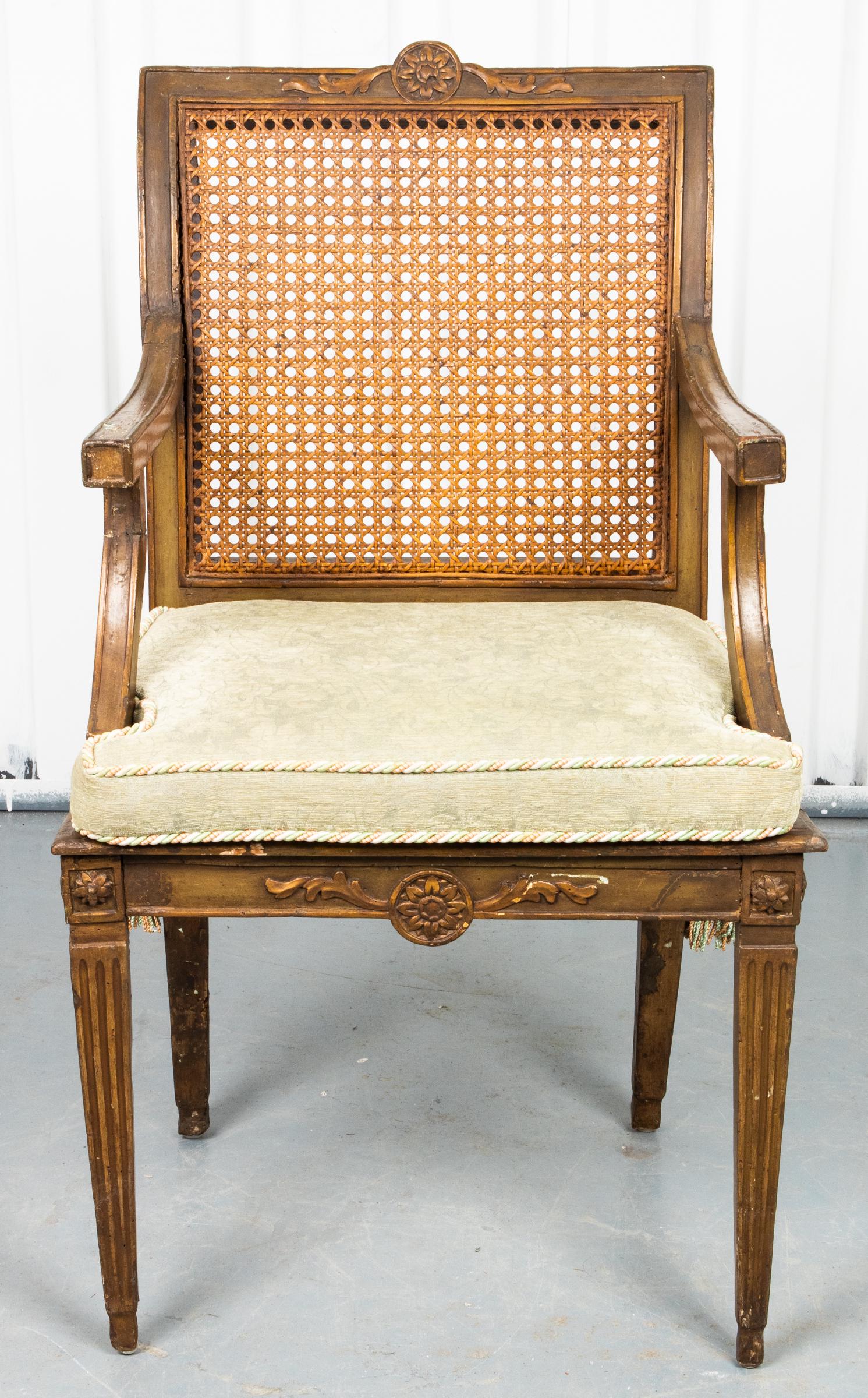 Louis XVI Style Caned Fauteuil: Louis XVI style fauteuil, the crest with central rosette medallion above the caned back, the upholstered seat cushion with passementerie trim raised on tapered square fluted legs. 38” H x 24” W x 