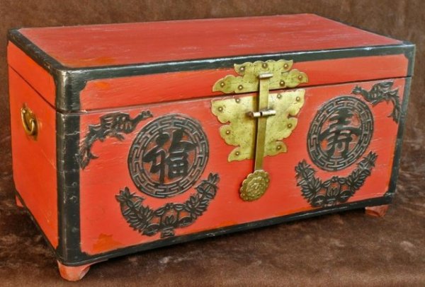 Red Antique Korean Wedding Chest: Footed wedding chest painted red with black outline with an ornamental brass lockplate in the shape of a lotus flower, hinges, and two side handles. Two phoenixes and the symbols for good fortune and 