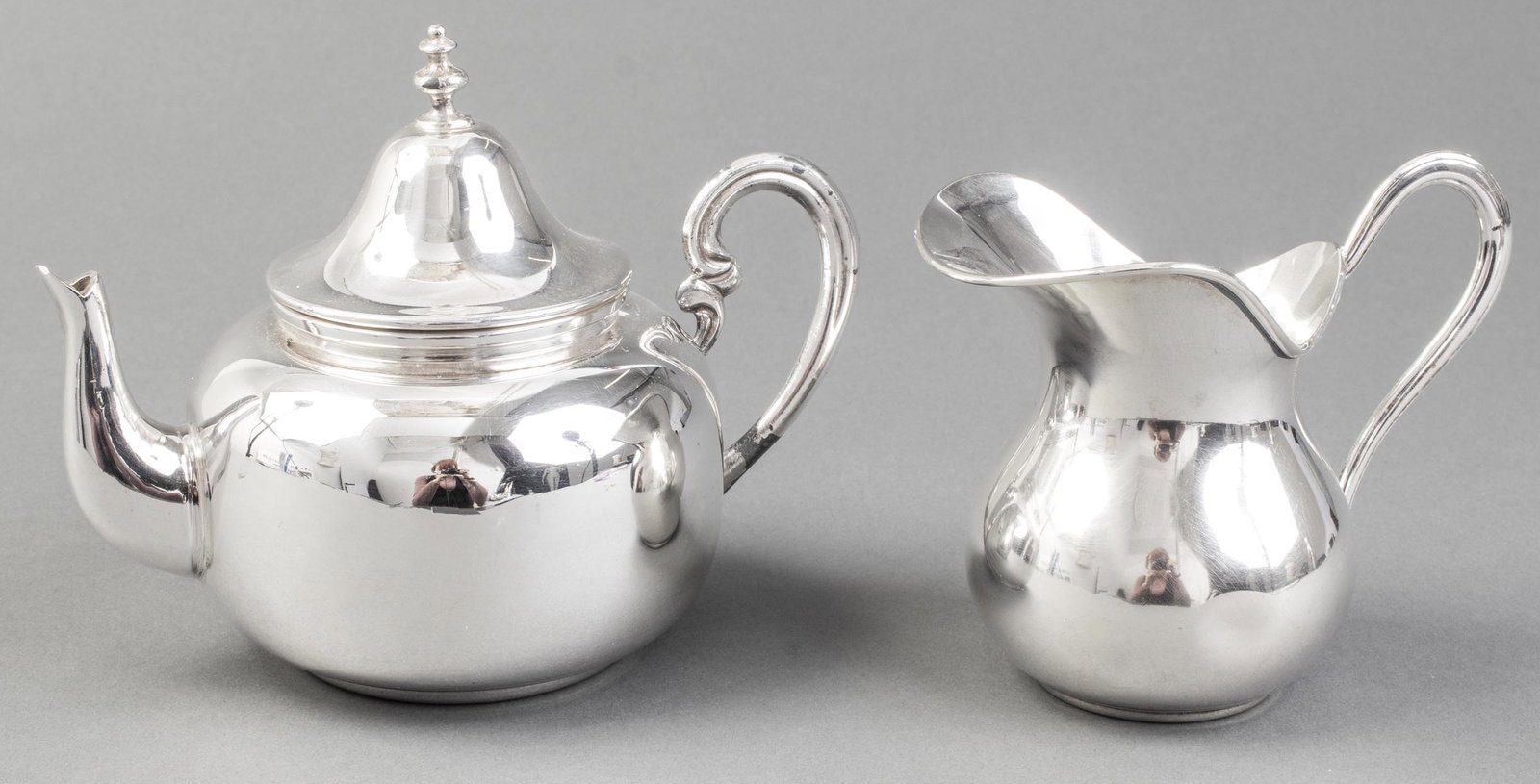 Modern Mexican Silverplate Teapot and Creamer, 2: Mexican silverplate teapot with bell within lid and unmatched creamer, teapot is marked to underside: "Hecho EN, Mexico." Teapot: 5.75" H x 6.5" W x 4" D. Dent to creamer and some loss to silverplate 