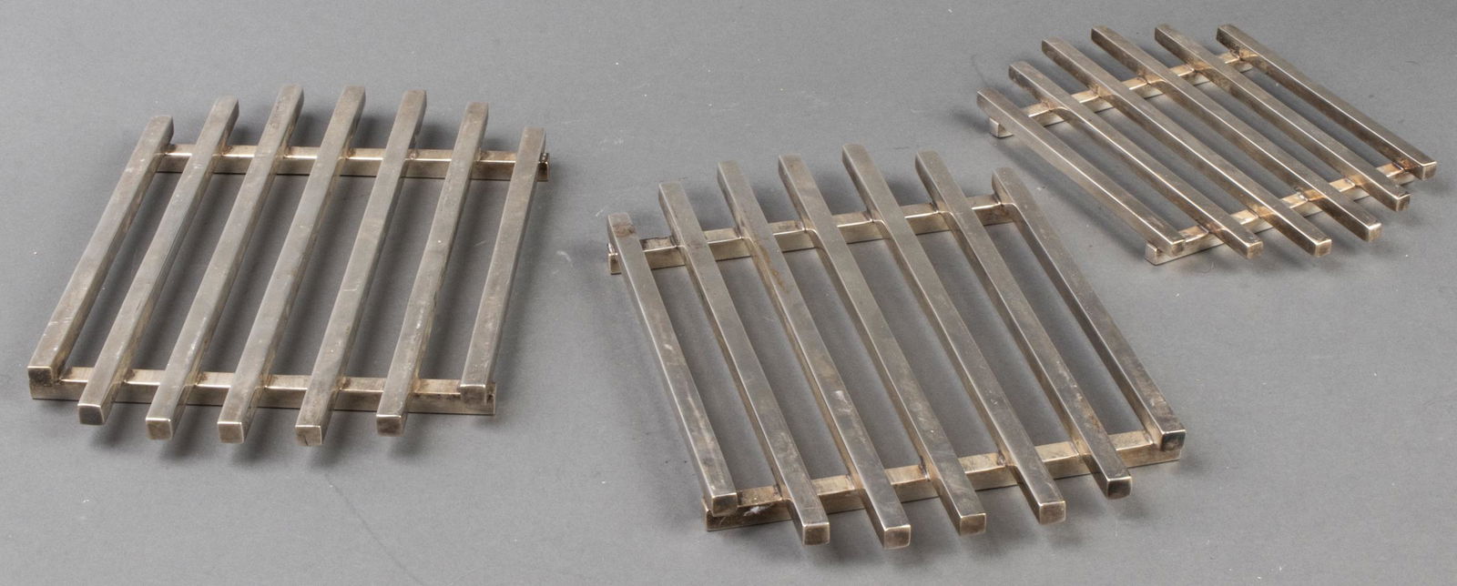 Modern Silverplate Trivets, 3 Pcs.: A trio of silverplate trivets with a modern design, two are matching 9.75" W x 6.75" D, one is 7.75" W x 5.5" D.