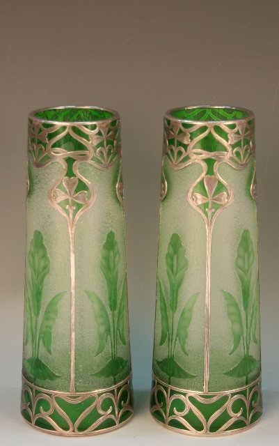 Pair of Art Nouveau Glass Vases w/ Silver Overlay: Pair of green-hued, art-nouveau-style vases featuring floral images and engraved swirling patterns, glass and frosted glass, silver overlay. Dimensions: Each 6-7/8"H x 2-1/8" diameter