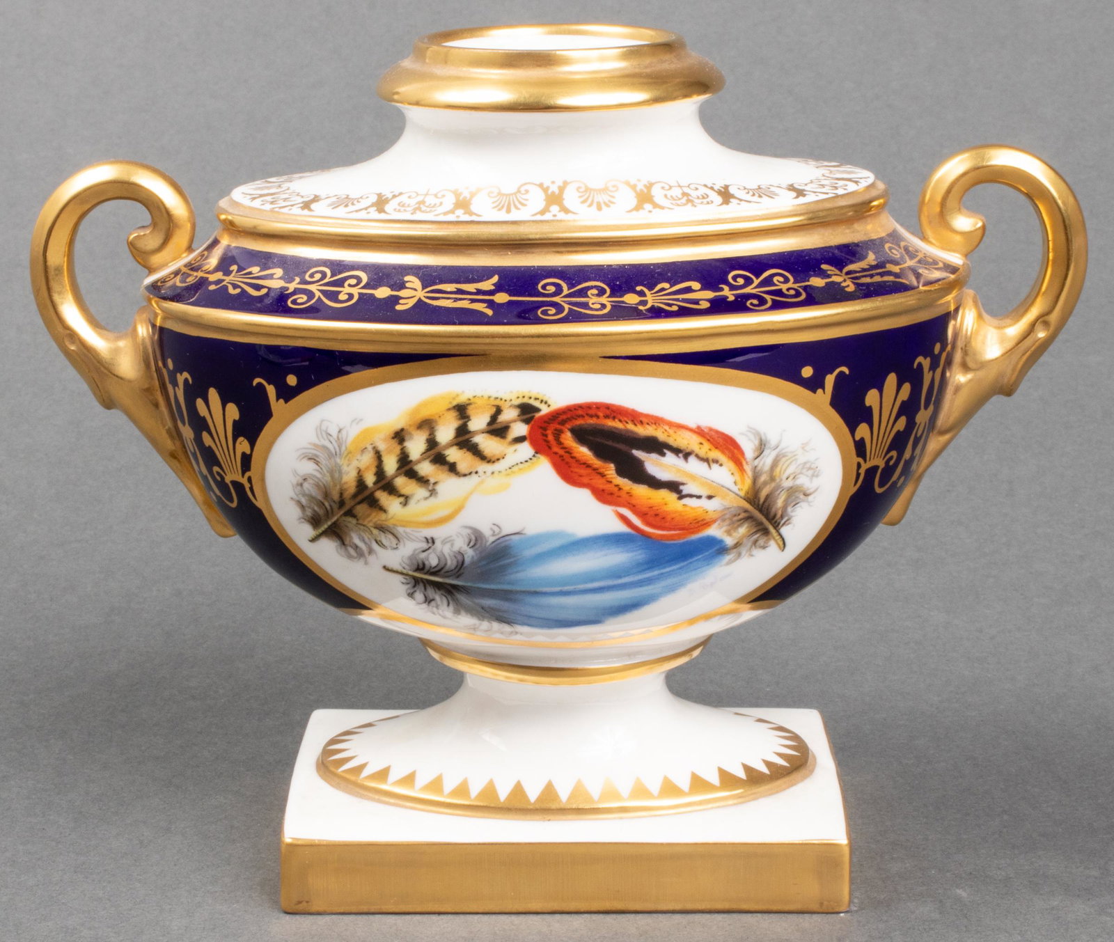 English Royal Worcester Royal Blue & Gilt Urn: The Worcester Heritage Collection urn, 2008, painted with feathers on a royal blue ground with gilt highlights. Maker's mark to underside. 5.5" H x 6.75" W x 3.5" D. Lid is missing.