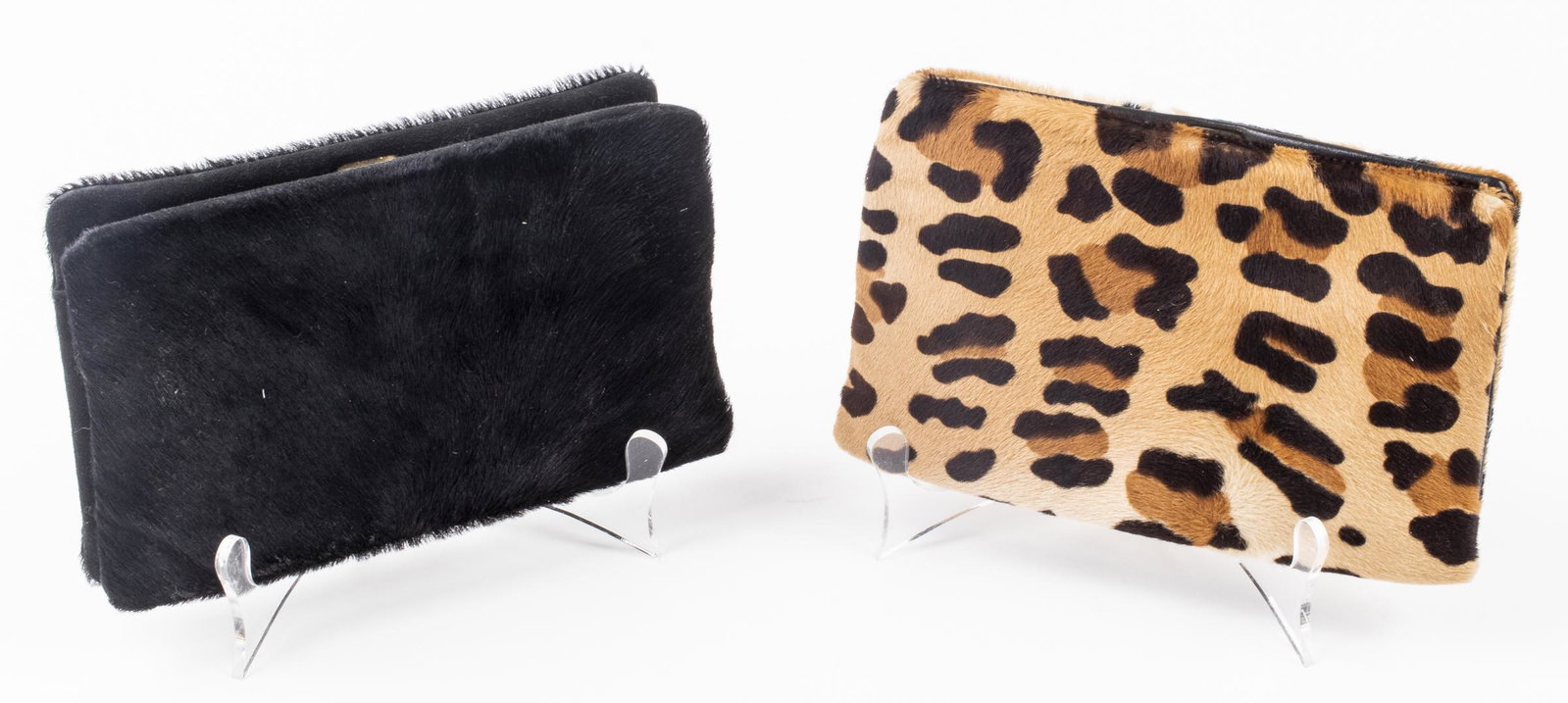 Donna Karan Hide Clutches, 2: Two Donna Karan hide clutches, one in black and the other with stenciled animal print, both with gold-tone clasps and three interior accordion compartments with zipper pouch. 5.25” H x 8” W x 2”