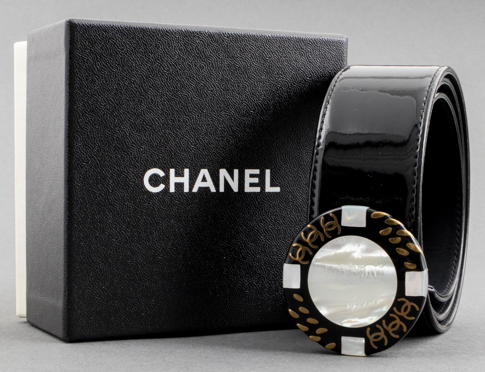 Chanel Black Patent Leather Casino Motif Belt: Chanel black patent leather belt with casino chip logo motif buckle, from the 1997 Fall (Automne) Collection, marked "Chanel Made In France" and size 75/30 to reverse, with Chanel box, with retail tag