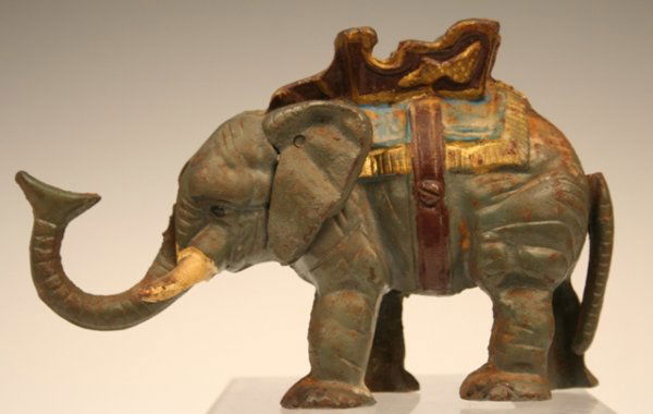 Hubley Mechanical Elephant & Howdah Bank 1934: Grey elephant with brown & gold howdah, and blue-and-gold blanket. This small sculpture is actually a mechanical bank that operates by pulling the animal's tail, by Hubley, cast iron, Americ