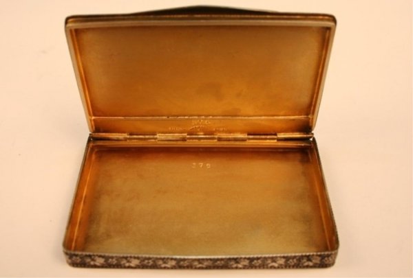 Sterling Silver & Enamel Victorian Cigarette Box: Small, rectangular blue cigarette box with a gilded interior, featuring a black, ovoid central panel picturing an incised floral and foliate Victorian design surrounded by a blue wave pattern and four
