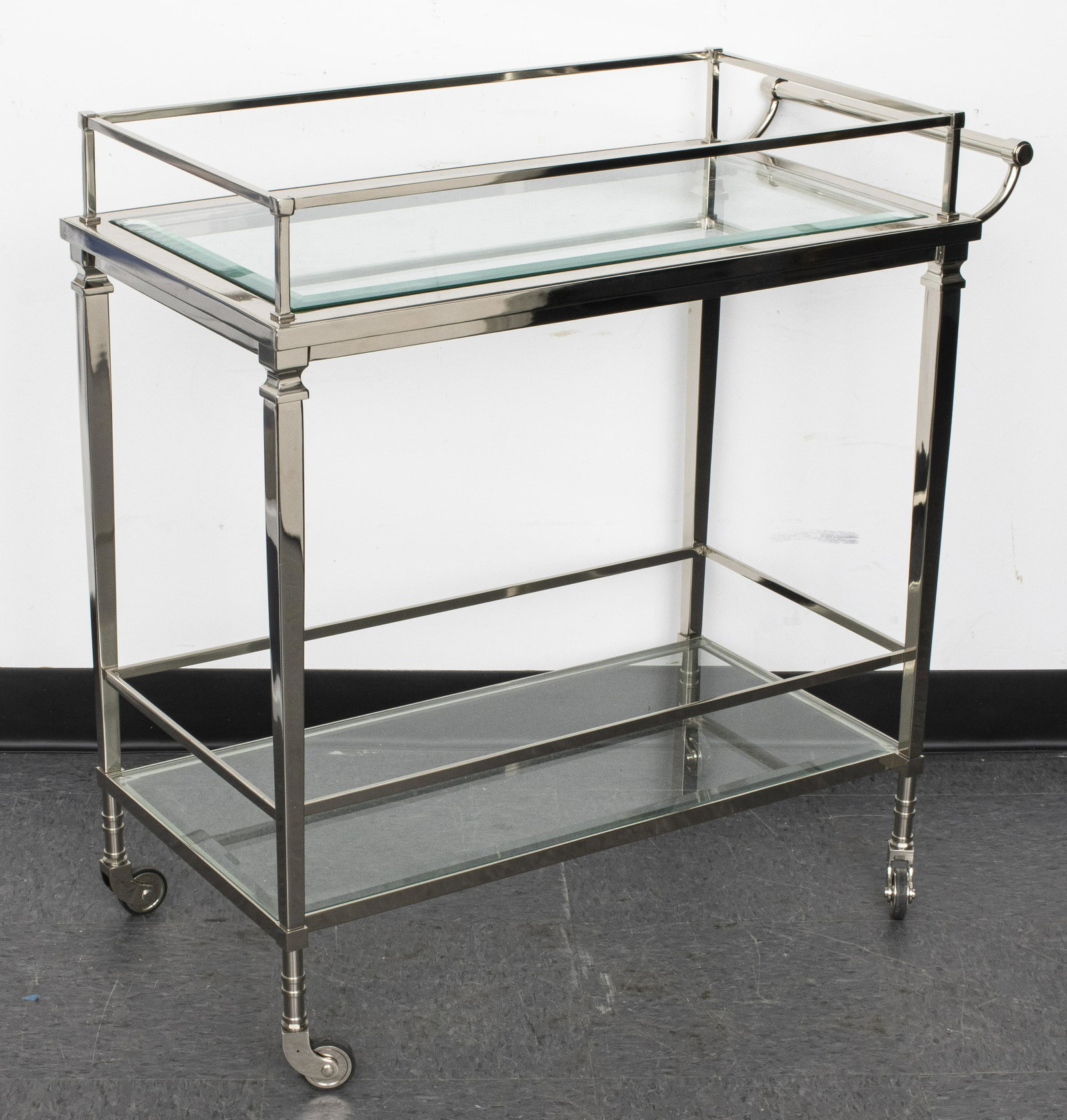 Modernist Chrome And Glass Bar Cart: Modernist chrome and glass bar cart with two tiers and casters. 33” H x 33” W x 17” D