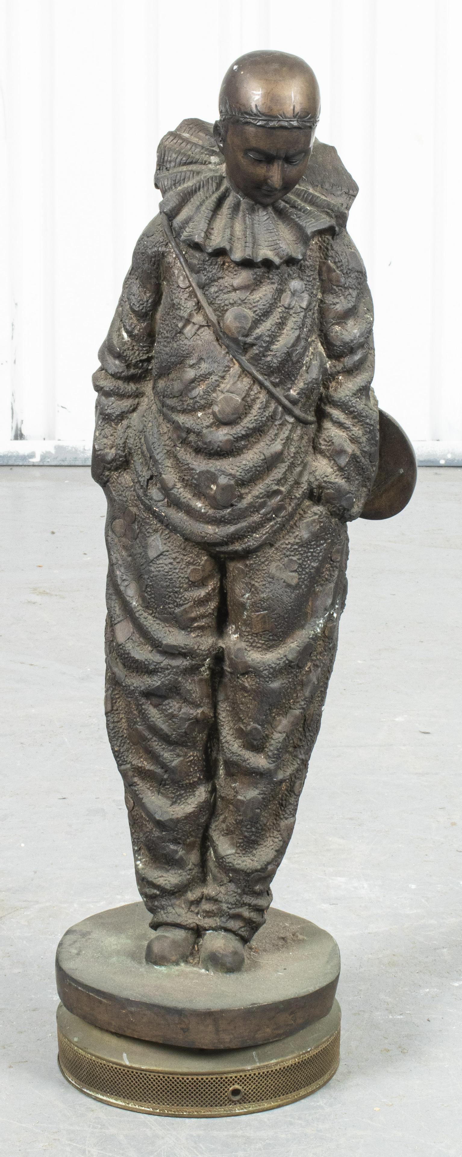 Cast Sculpture of a Harlequin Clown: Bronze and cast iron sculpture of a harlequin clown, modeled with ruffled collar, looking down with hands in pockets. 25.5Â” H x 9.5Â” diameter.