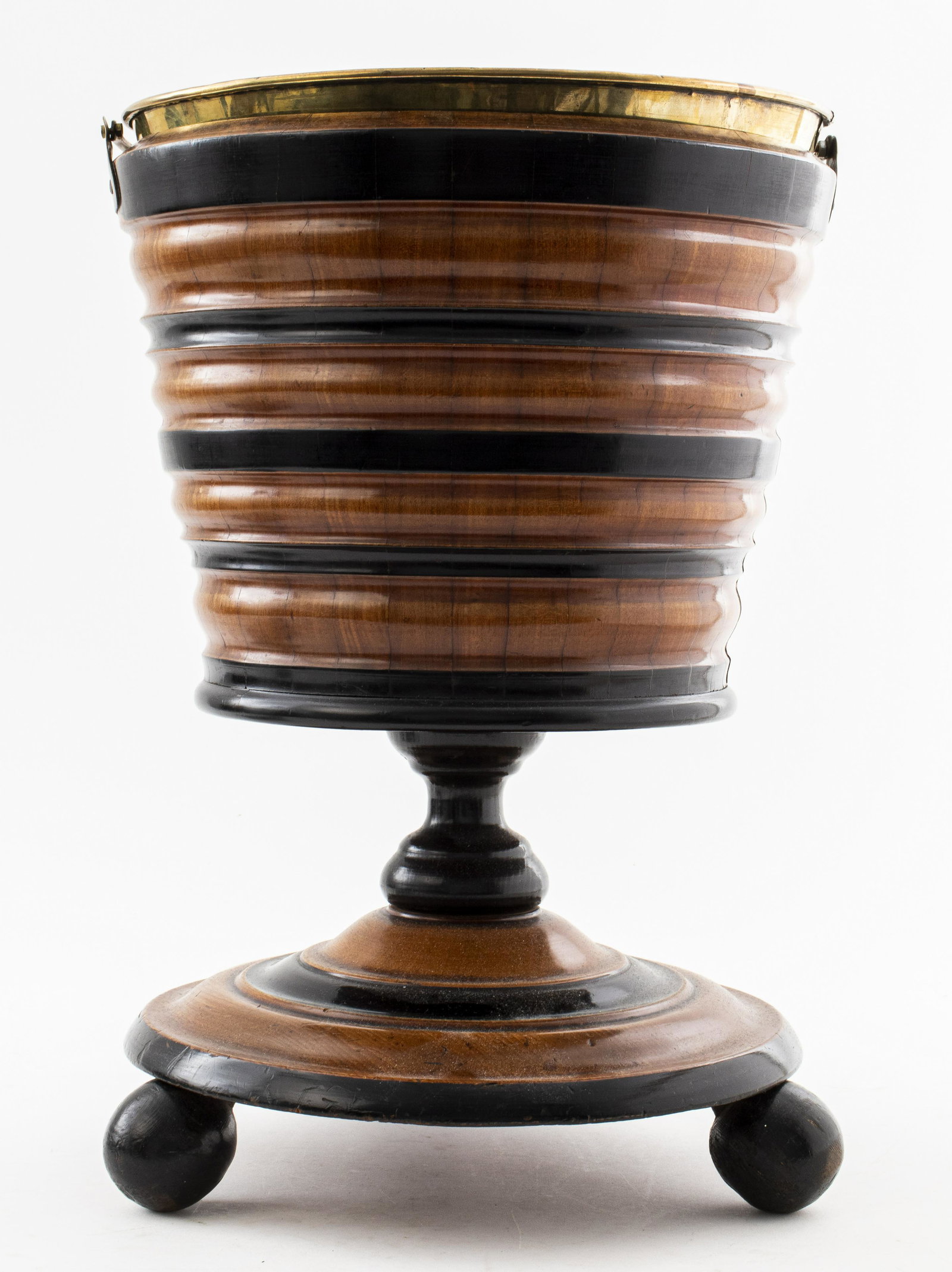 English Victorian Parcel Ebonized Peat Bucket: English Victorian peat bucket or wine cooler, mid 19th century, mahogany with brass liner and swing handle, of ribbed form with contrasting parcel ebonized bands, raised on three ball feet. 16.5" H x 