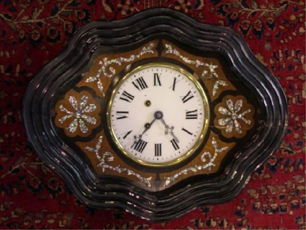 French Oeil-de-boeuf Mother of Pearl Wall Clock: French oeil-de-boeuf ebonized wood wall clock with mother-of-pearl inlay, reverse painted glass dial with Roman chapters and serpentine edge, France; unmarked. Dimensions: 20"L x 15-1/2"W x 5-1/2"D