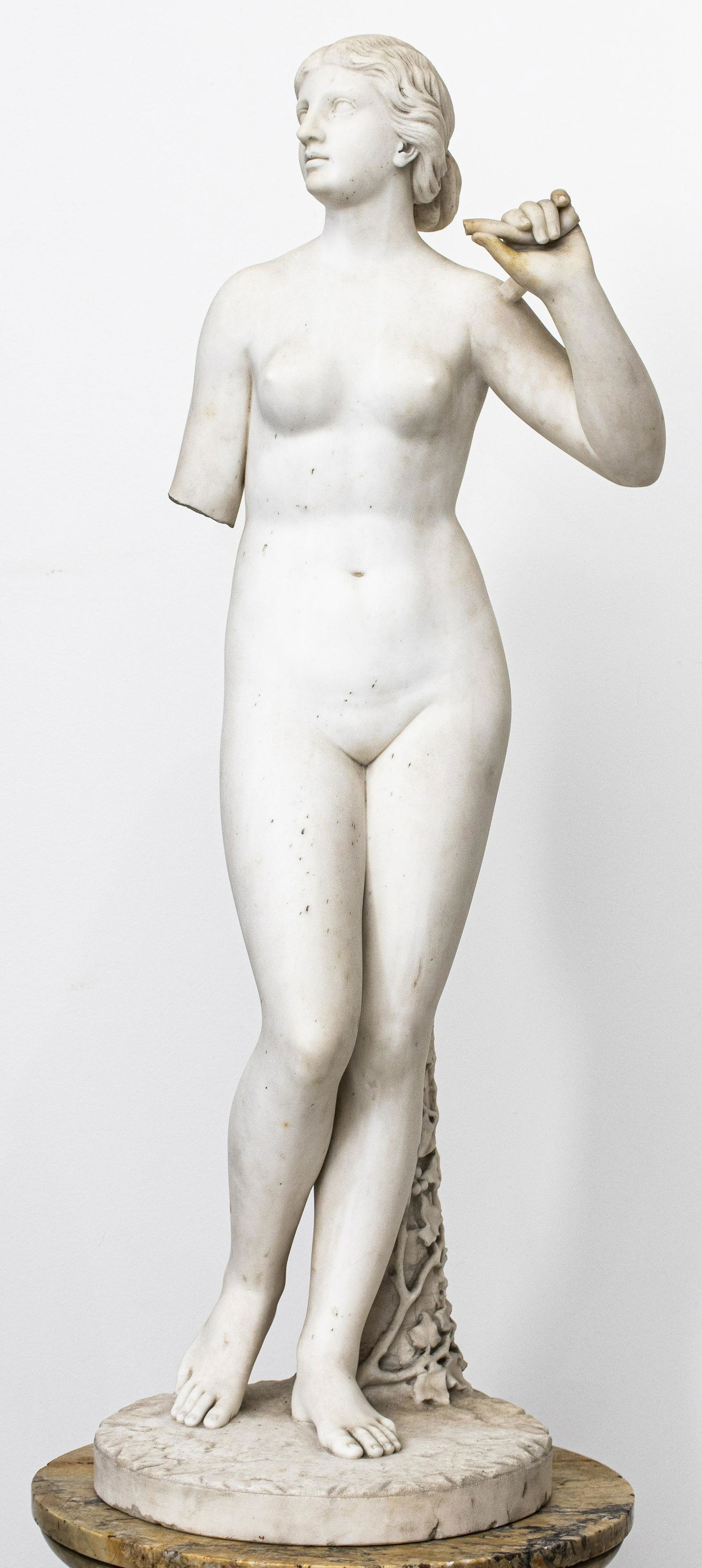 Academic Marble Aphrodite Sculpture on Pedestal: Academic neoclassical style marble sculpture of Aphrodite, raised on column pedestal, possibly American academic period, in style of Hiram Powers or Harriet Hosmer. Sculpture: 37" H x 12" Diameter. Pe