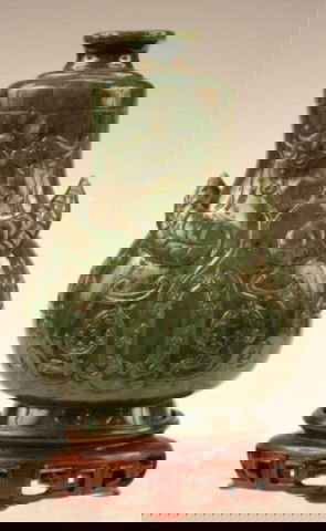 Qing-Era Chinese Carved Spinach Jade Lidded Bottle: Lidded bottle with hand-carved decoration on a carved wood stand, spinach jade, China, Qing Dynasty (1644-1912), late nineteenth or early twentieth century. Dimensions: Approximately 6-1/8"H x 3-3/4"W