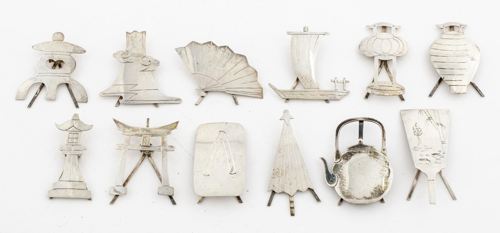 Chinese Silver Place Card Holders, 12 PCS.: Whimsical silver place card holders depicting various forms including a stylized volcano, teapot and fan, marked "silver" to reverse, approx.1.61 ozt.