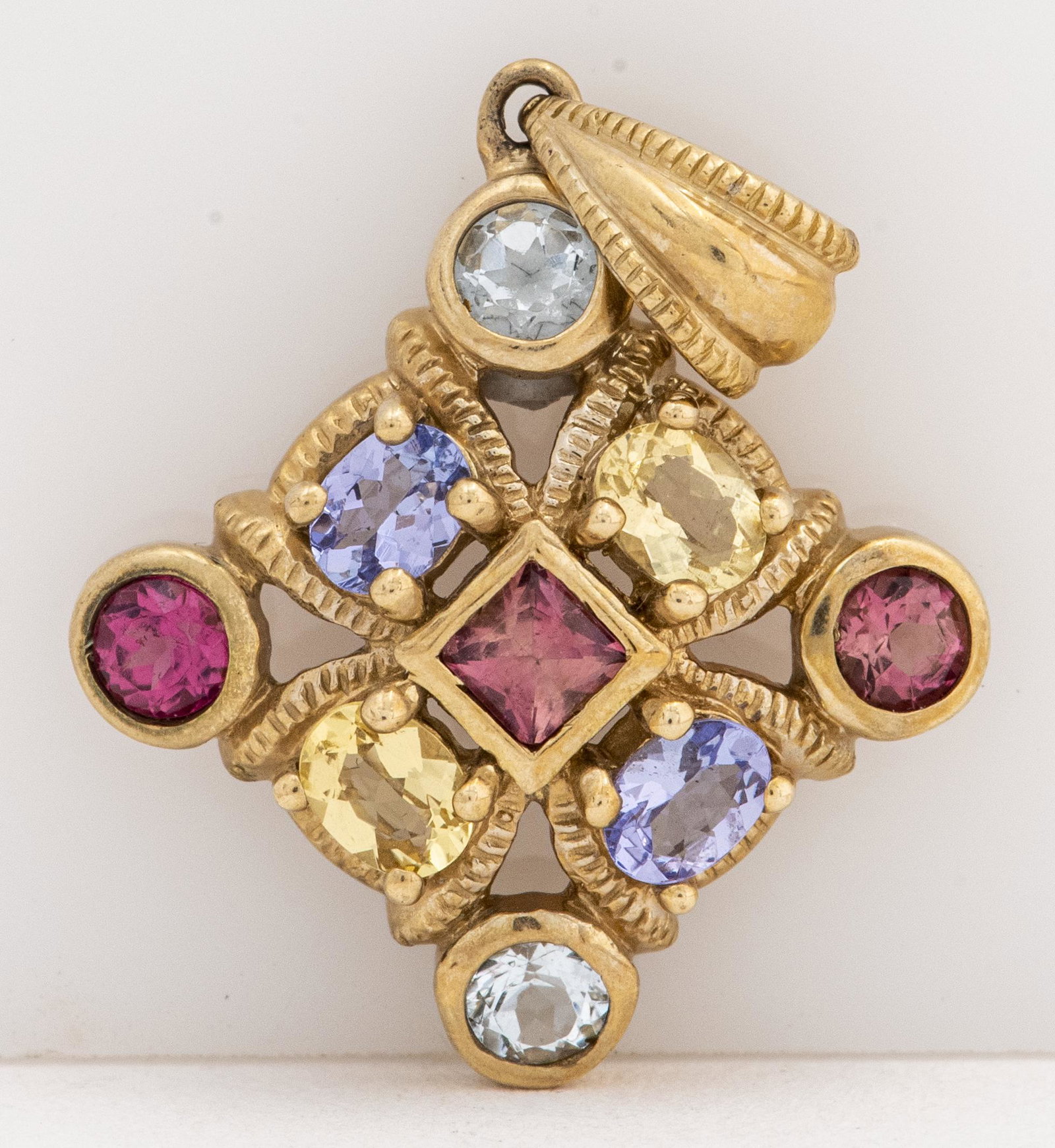 Vintage 10K Yellow Gold Colored Gemstone Pendant: Vintage 10K yellow gold colored gemstone pendant, comprise of nine colored gemstones: tanzanite, tourmaline, citrine and aquamarine surrounded by ribbed detail borders, marked "10K / THL." Pendant mea