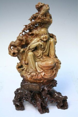 Chinese Soapstone Carving Late 19th-Early 20th C.: Intricate carving of a seated male scholar in draped robes with meandering tree forms behind him, soapstone, China, late nineteenth or early twentieth century; marked. Piece stored in cloth-covered bo