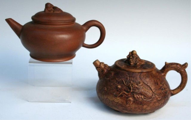 Lot of 2 Chinese Yixing Clay Teapots: Lot of two light brown Yixing teapots, one with dragon motif in low relief, China; each marked on bottom. Dimensions: Smooth teapot approximately 4"H x 7-1/2"W; dragon teapot approximately 4-1/4"H x 6
