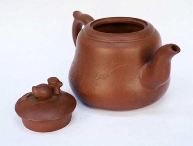 Chinese Yixing Clay Teapot: Teapot with peach on lid, incised floral decoration on one side of body, and calligraphy on the other, Yixing ceramic, China; marked on bottom. Dimensions: 4-1/2"H x 7-1/2 "W