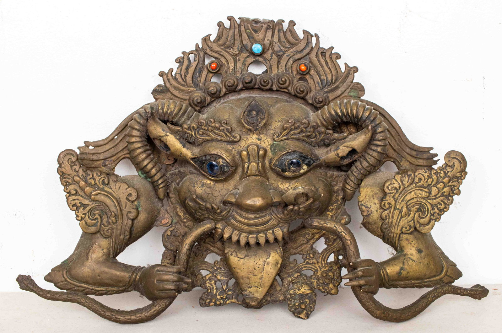 19th Century Nepalese Bhairava Brass Mask: 19th century, Nepalese Bhairava mask, showing the depiction of Shiva as Bhairava, "The Terrifying One," with snakes in his hands, fiery facial hair and a jeweled crown, brass with glass eyes as well a