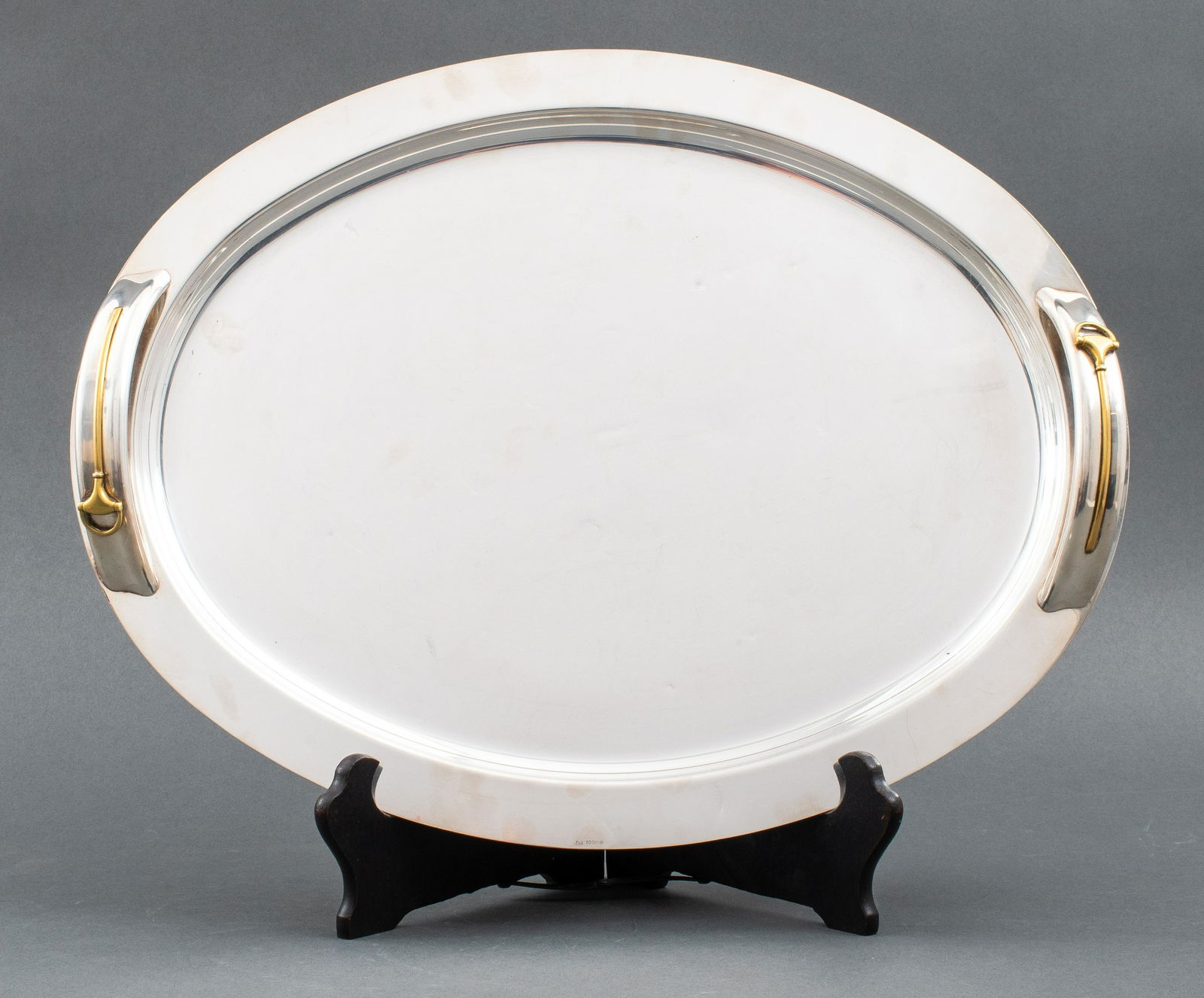 Gucci Stainless Steel & Brass Modern Tray: Gucci modern stainless steel & brass oval two-handled tray, handles decorated with iconic Gucci stirrups motif, descending from the equestrian roots of the company, marked "Gucci / Italy." 2" H x 19.2