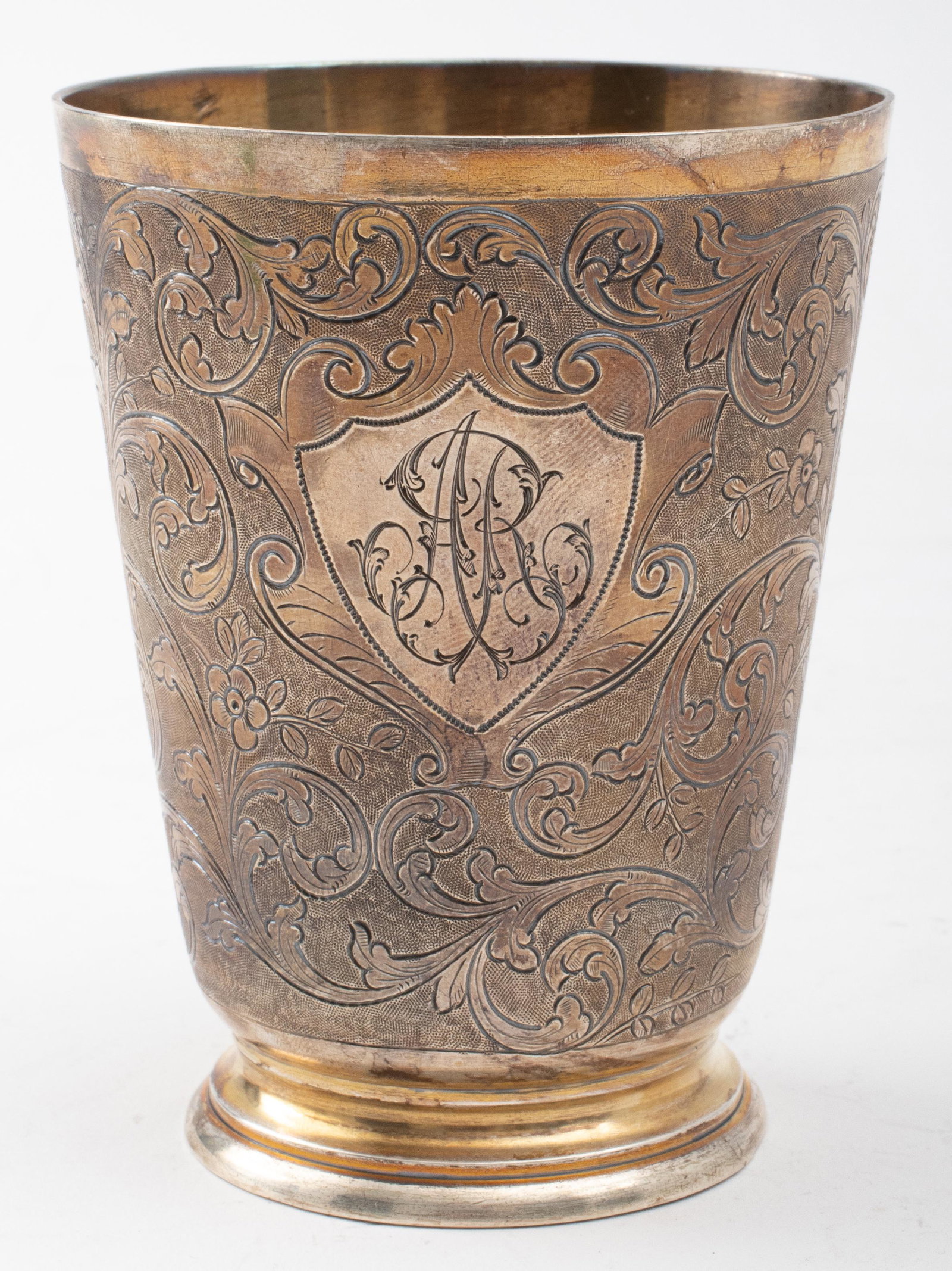 French Gilt Silver Engraved Beaker: A French gilt 950 silver footed beaker engraved with scrolling foliate tendrils, monogrammed "A R," assay mark on the rim and maker's mark on the reverse. 3.5" x 2.75" W. Weighs 4.37 ozt.
