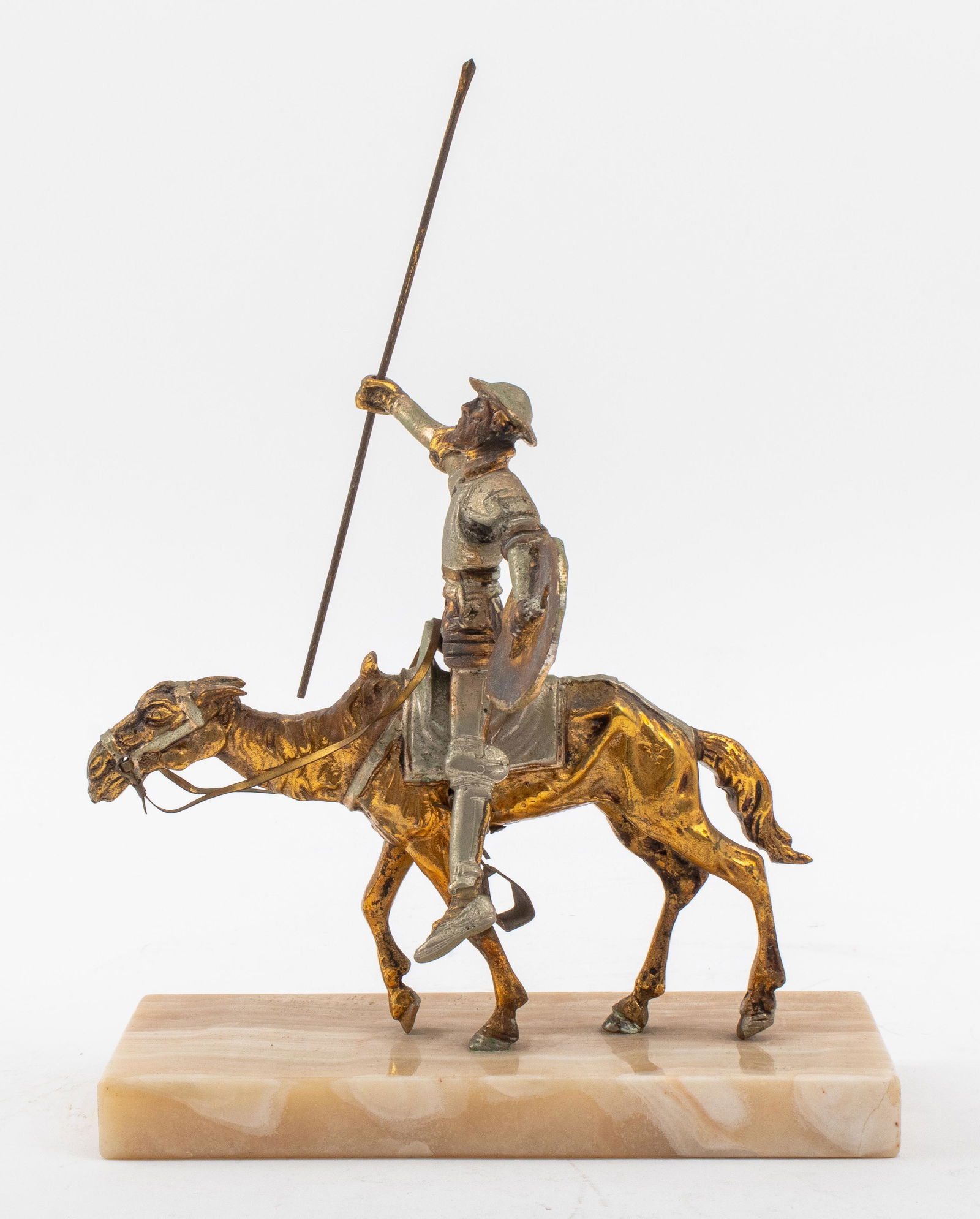 Gilt Bronze Statue of Don Quixote on Rocinante: Gilt bronze sculpture of Don Quixote riding his horse, Rocinante, and wielding a shield and staff, mounted upon a banded agate base, no apparent mark. 9.75" H x 7" W x 3.25" D.