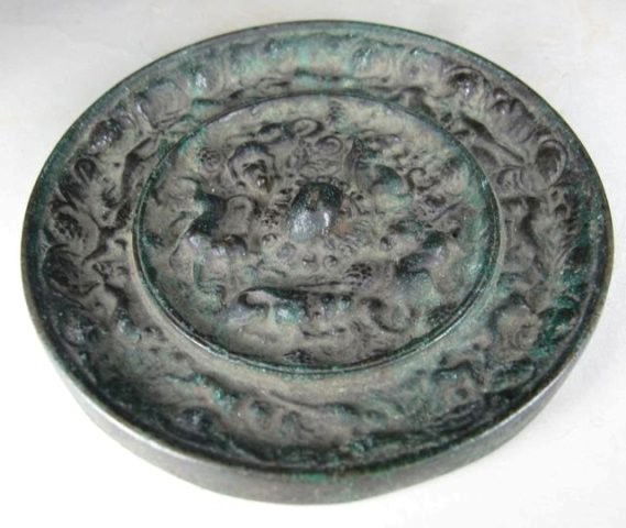 Chinese Bronze Mirror Tang Dynasty: Bronze cast in high relief, the inner field with scroll radiating from a central knob then flanked by various crouching, reclining, and prancing lion-like mythical beasts amidst fruiting grapevines, t