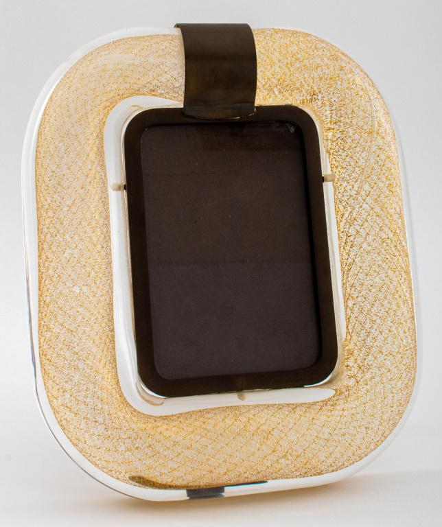 Tommaso Barbi Murano Glass Bronze Mounted Frame: Tommaso Barbi (Italian, XX) golden helix shaped glass centering a bronze frame with a mount to cover the glass joint, the strut signed "Tommaso Barbi / Made in Italy." Aperture: 6" H x 4" W; frame: 11