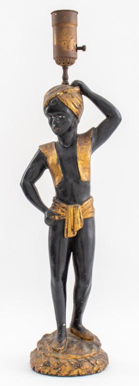 Venetian Ebonized & Gilded Wood Blackamoor Lamp: Venetian ebonized and gilded carved wood blackamoor lamp in the form of a turbaned Nubian with vest and loincloth, one arm above his head and the other on his hip, standing on a gilded circular plinth