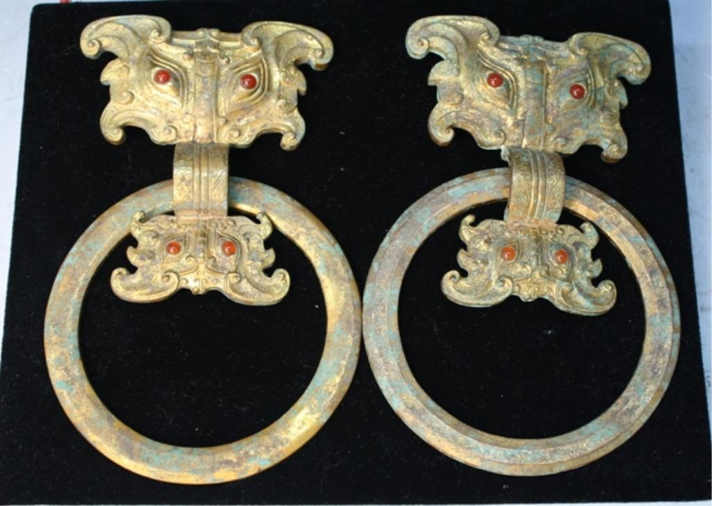 Pair of Chinese Gilded Bronze Taotie Masks w/Rings: Pair of taotie masks with rings and inlaid eyes, gilded bronze, China; unmarked. Dimensions: Overall 7"L x 4-1/2"W; each mask approximately 4-1/2"L x 3-7/8"W; each ring 4-1/2" diameter
