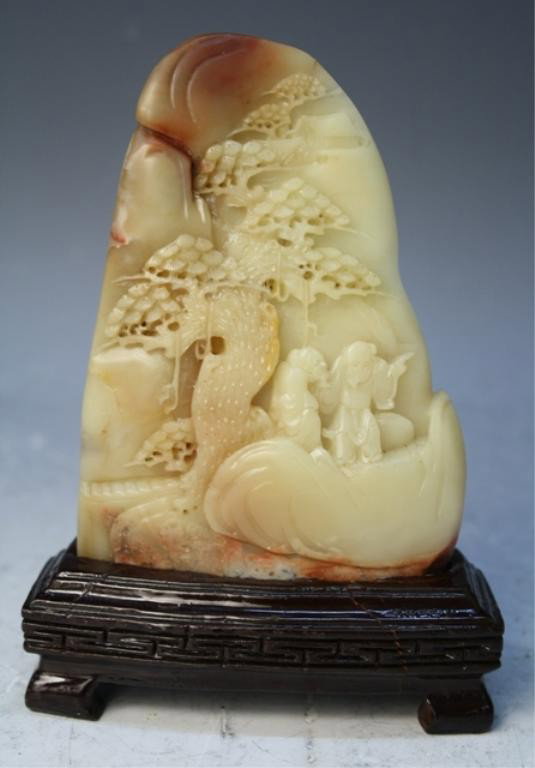 Chinese Baifurong Carved Soapstone Boulder: Baifurong soapstone boulder with carved figural scene, with lacquer wood stand, China; unmarked. Dimensions: with stand 6"H x 4-3/8"W x 1-3/4"D; without stand 5-1/8"H x 3-1/2"W x 7/8"D